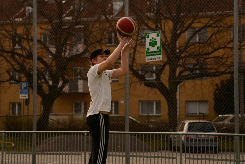 a man is trying to dunk the basketball in a parking lot