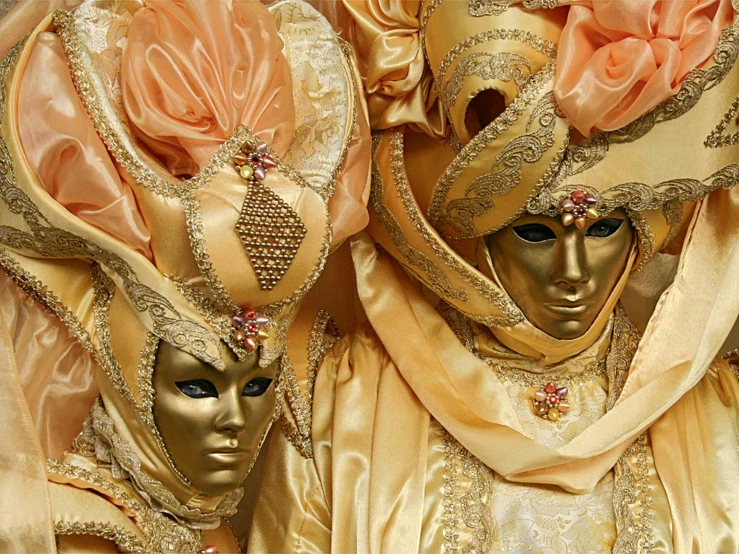 three women wearing masks and golden cloths