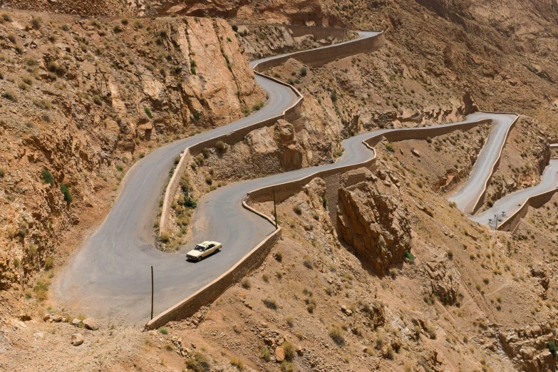 a road cuts through the mountains with a car going the same direction