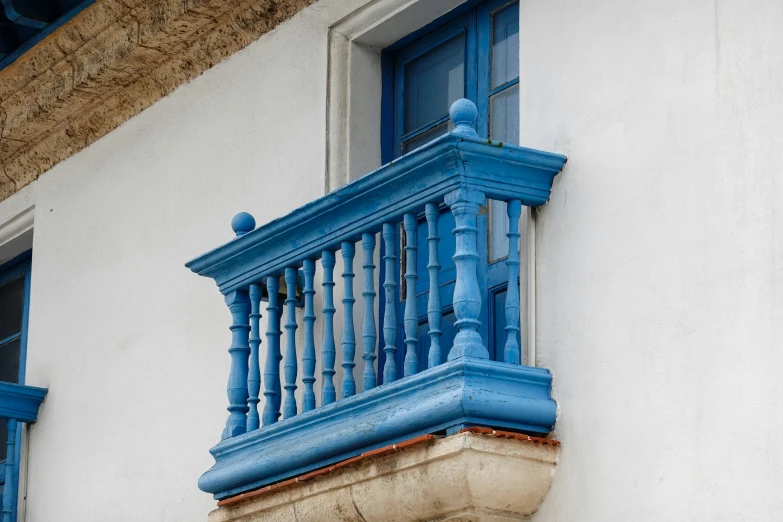 a blue window with wooden balconies sitting on a white building