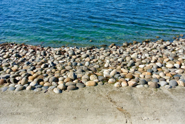 a close up image of rocks and pebbles next to water