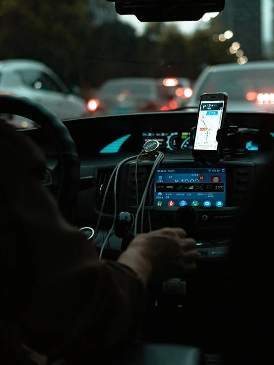 a man driving in the night with his cell phone on his dashboard