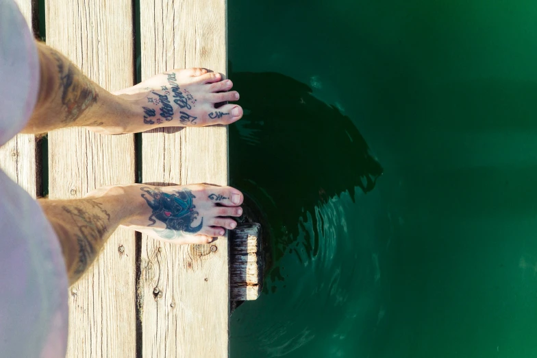 a woman standing on top of a wooden dock next to water