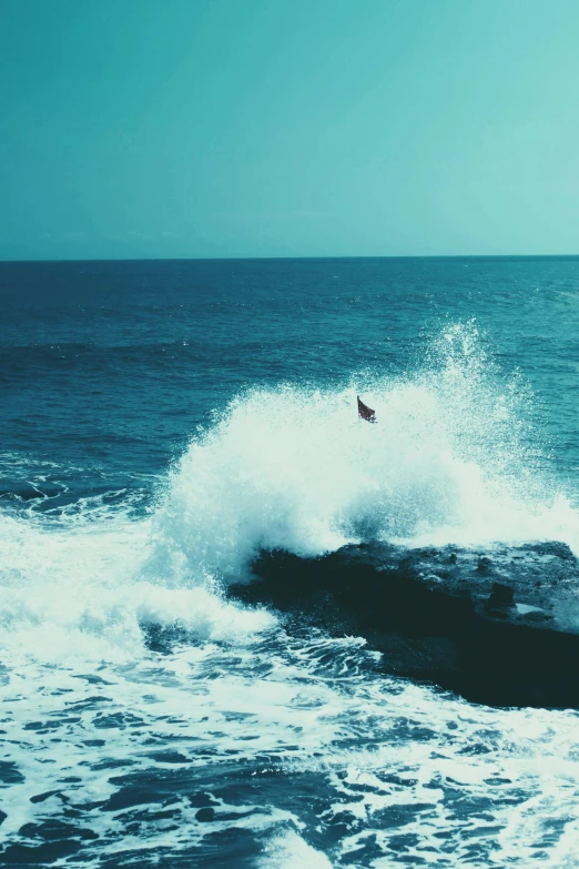 person surfing on an ocean wave, with blue sky