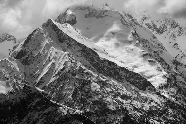 a mountain covered in snow under a cloudy sky