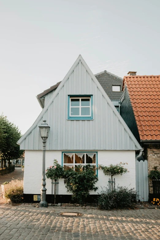 the white and grey house has a large red roof