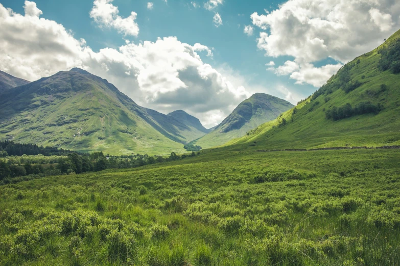 green mountains, grass and blue skies with a bright blue sky