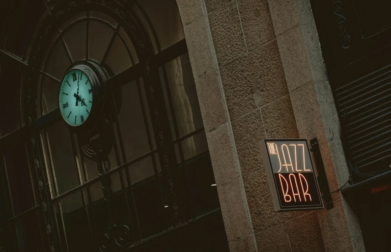 an illuminated sign below a large clock on the side of a building