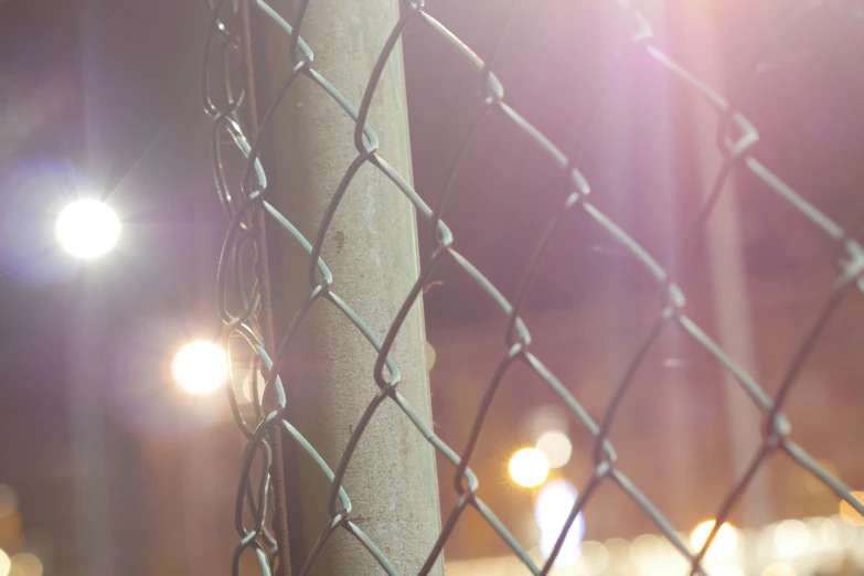 a close up po of a fence with the lights shining in the background