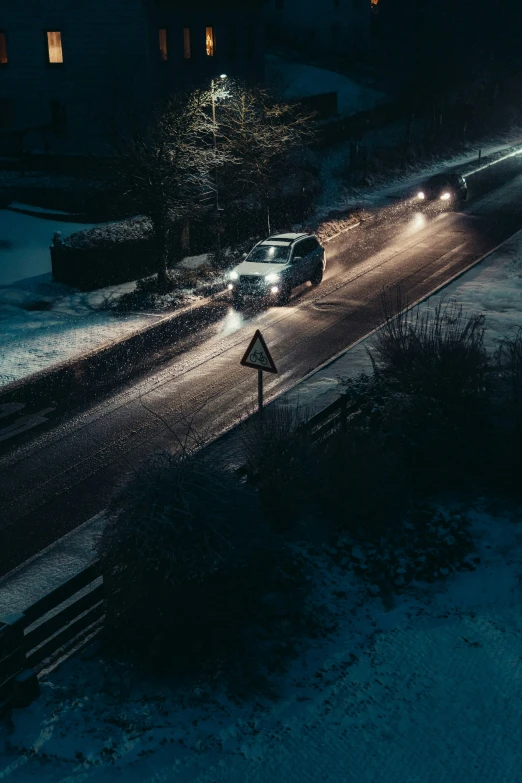 a night time view of a snowy road with several cars driving on the road