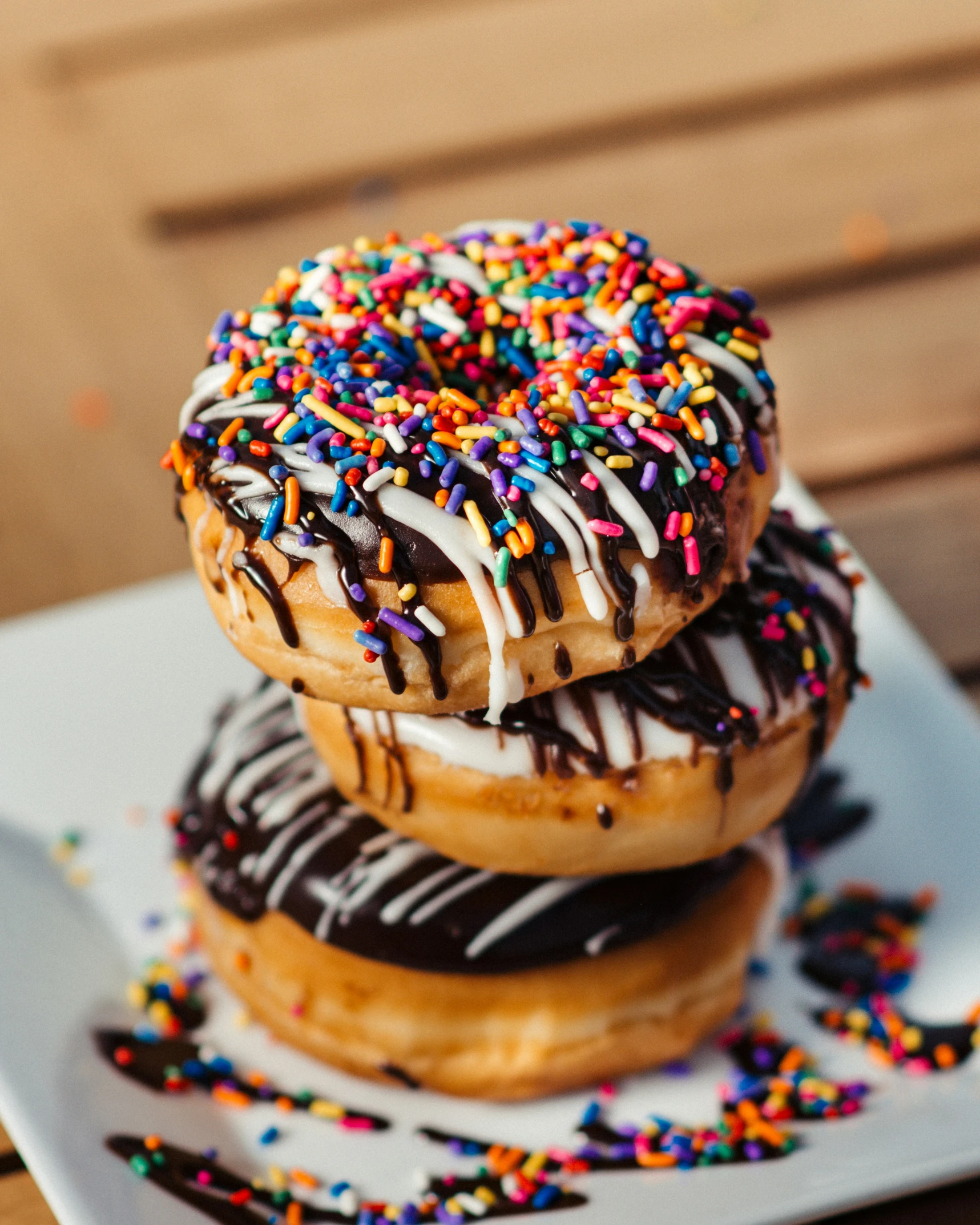 three donuts with chocolate and colorful sprinkles on a plate