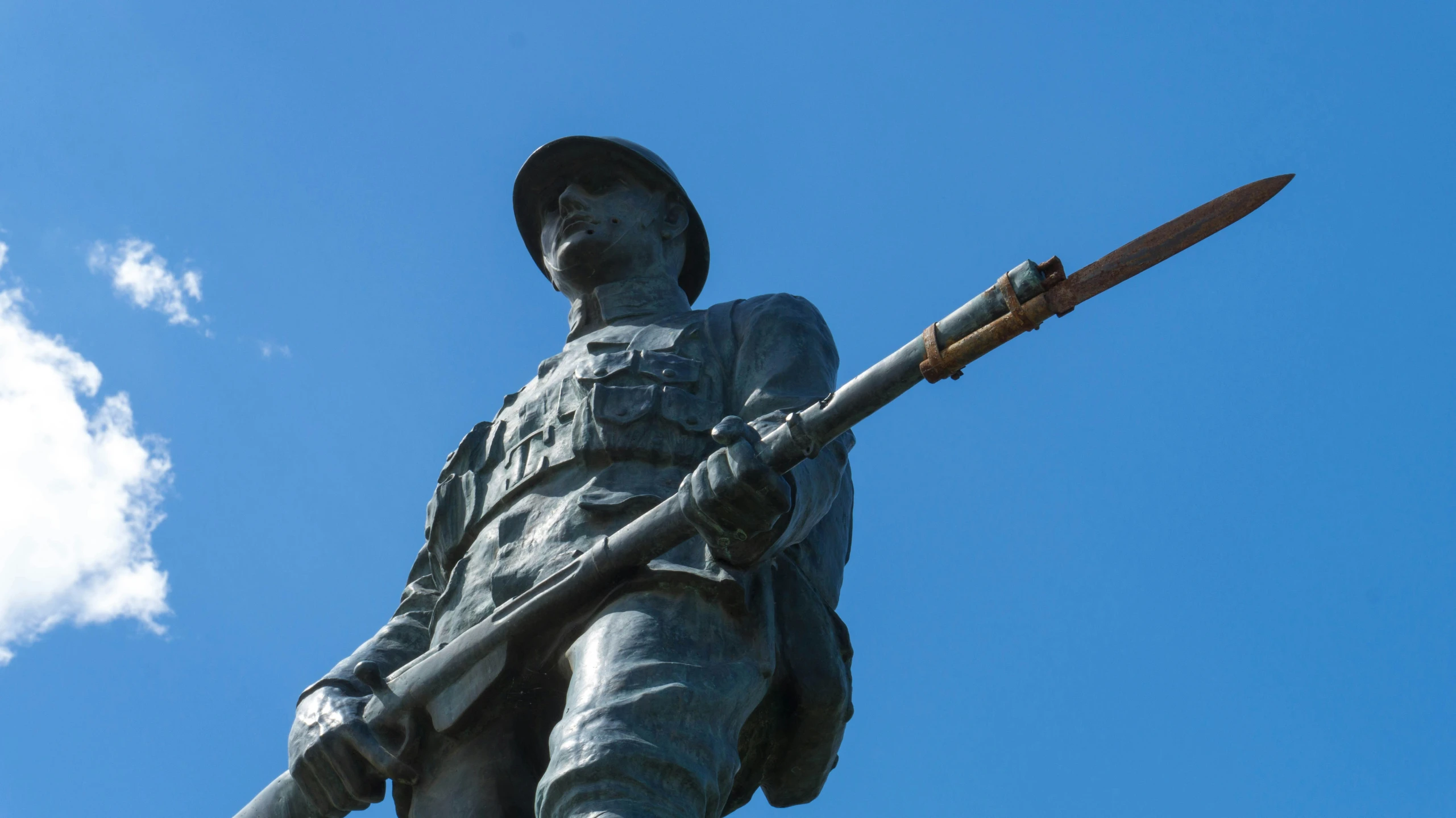 the soldier statue with a large rifle is near clouds