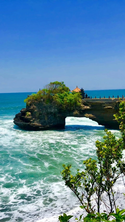 people stand at the top of a rock formation on the ocean