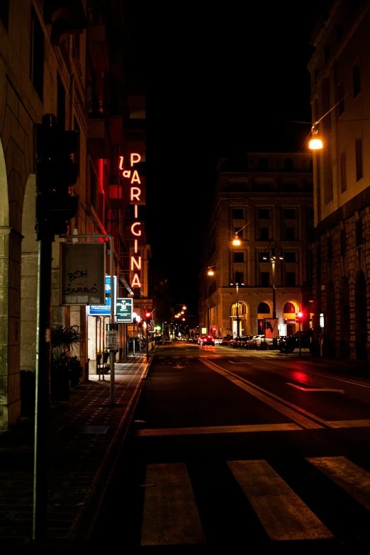 a street with lights on the buildings and a crosswalk