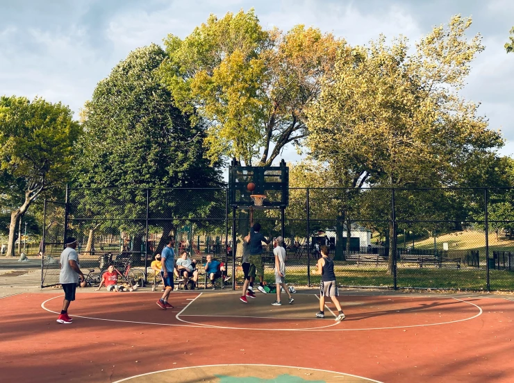 an outdoor basketball court with some people playing