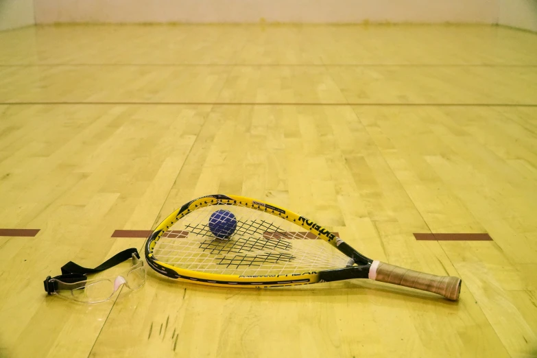 a tennis racket on the floor with a tennis ball inside