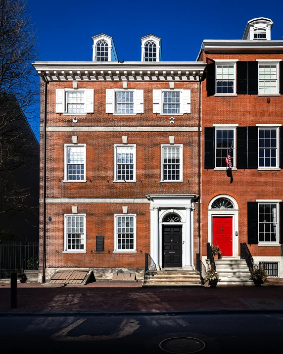 an old brick building with white windows and a red door