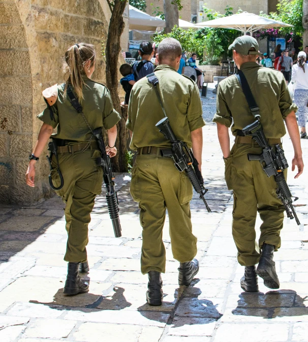 three military men and two women wearing uniforms are walking in front of a building