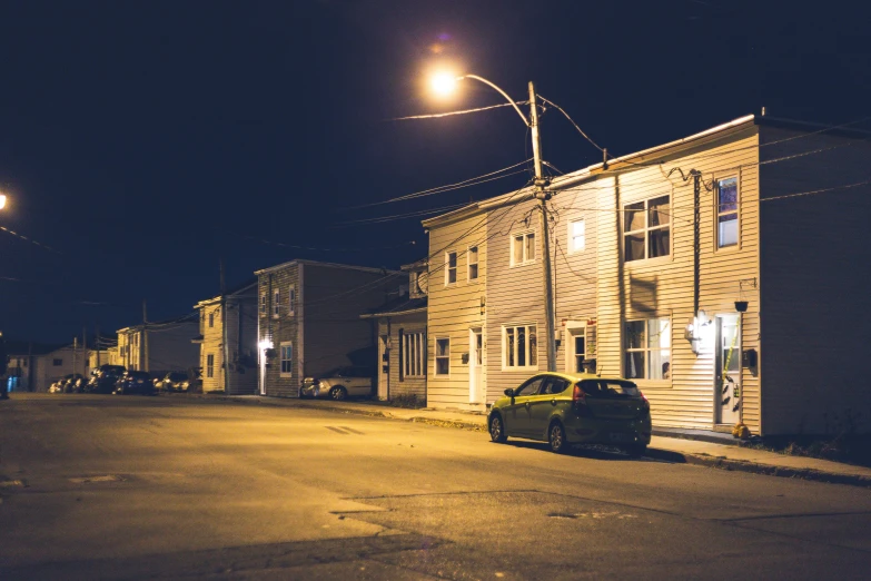 two cars parked on the road in a dark neighborhood at night