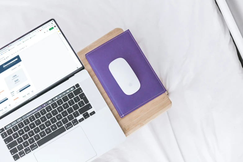 a white laptop with a purple case next to it