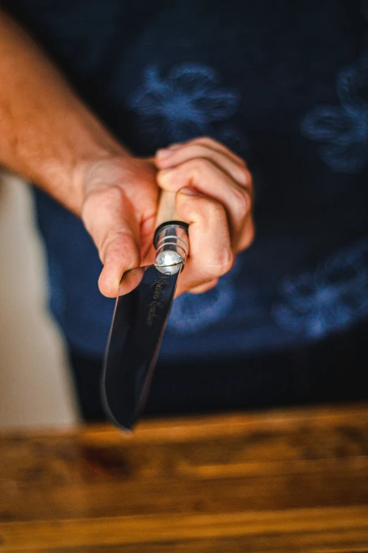 the hand is holding the knife while the other hand is on the table