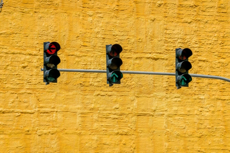 three stop lights on the street are hanging from a pole