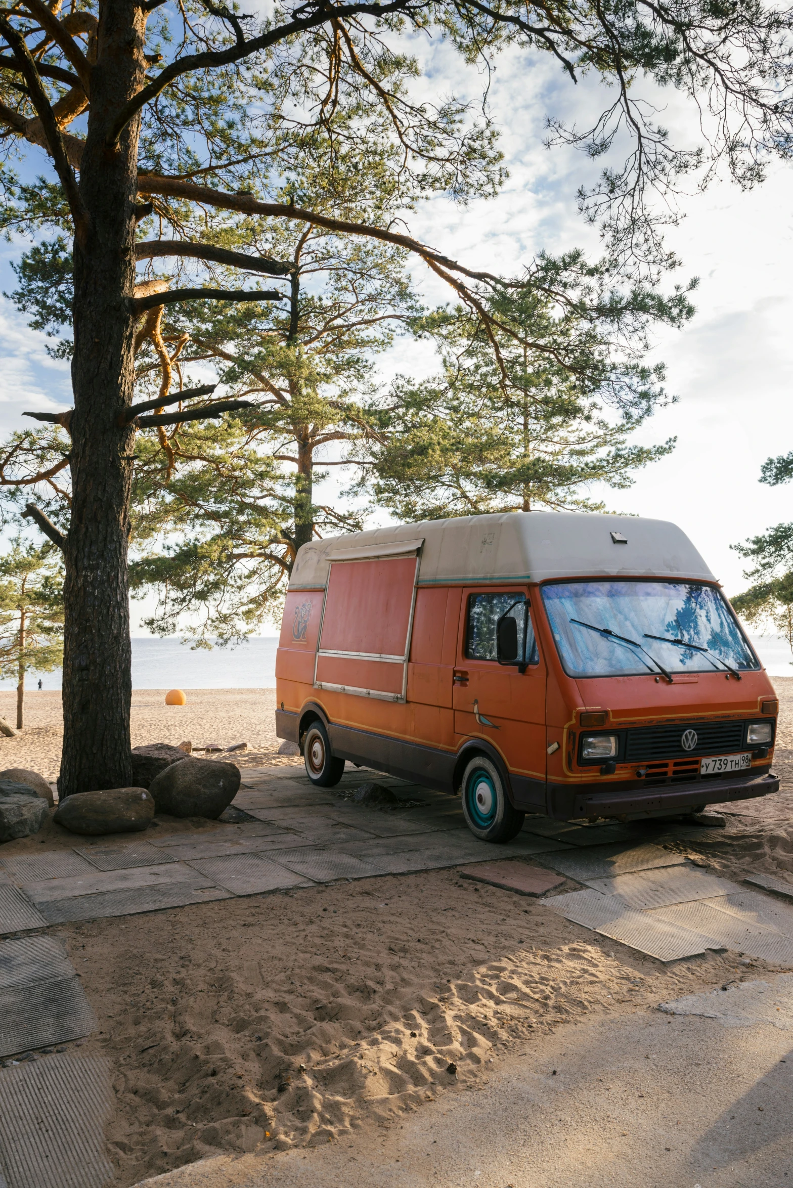 a orange van parked by a large tree