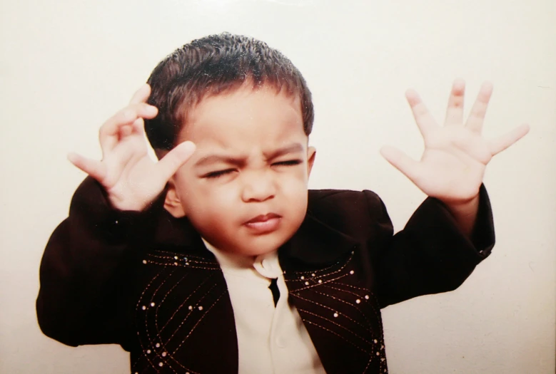 a child in a suit making the letter x