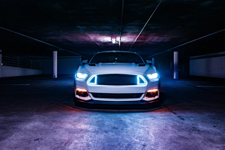 a white car is illuminated in a dark garage