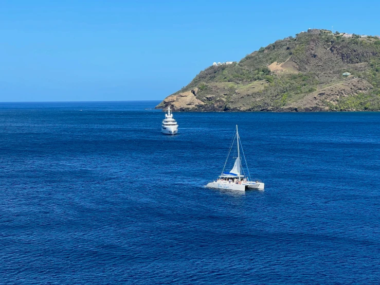 two sail boats are traveling side by side across the ocean