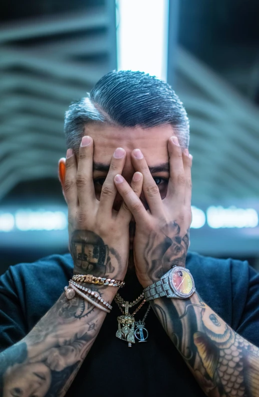 tattooed man with a hand covering his face