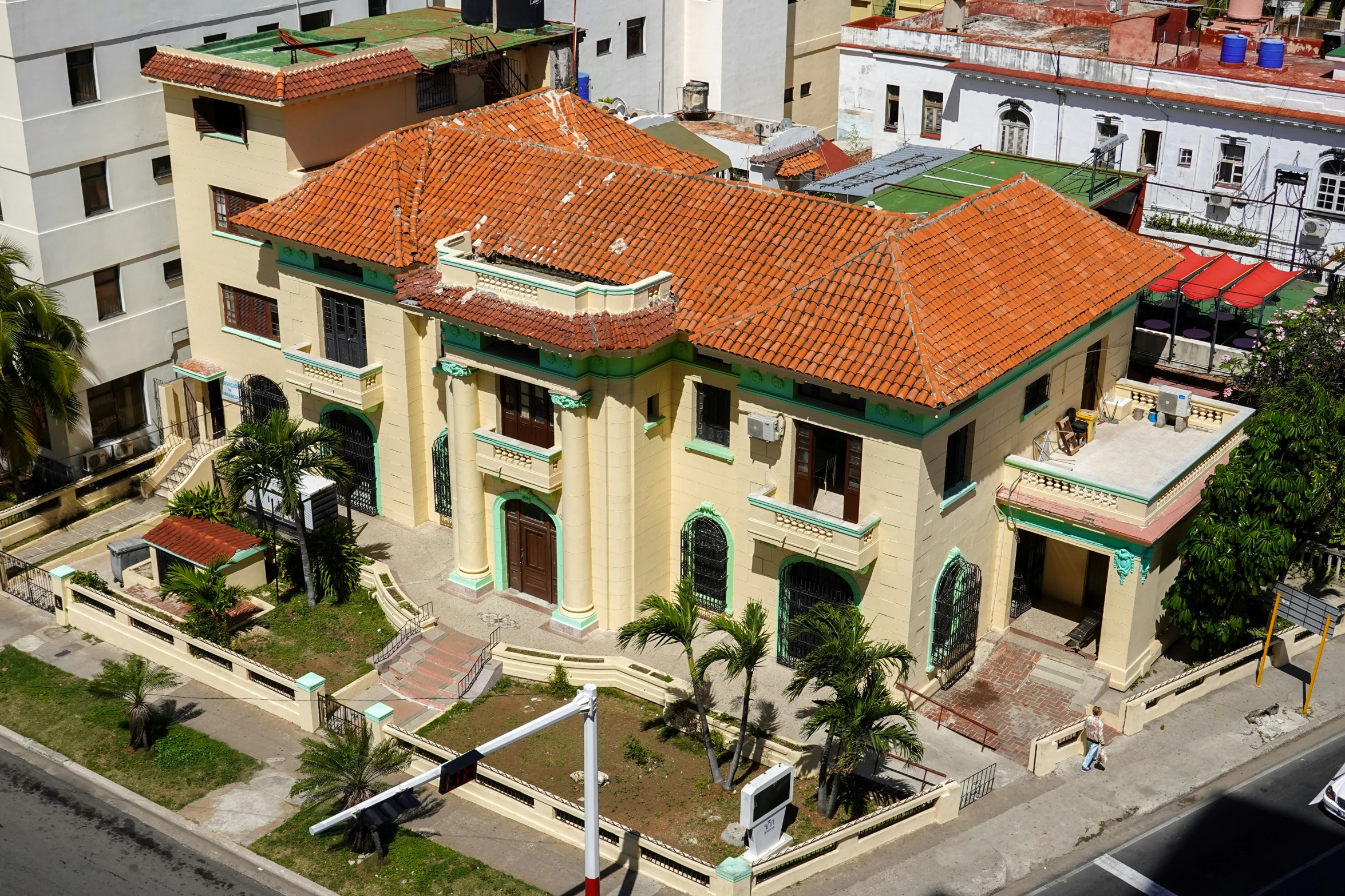 an aerial view of a yellow building with red tiled roofs