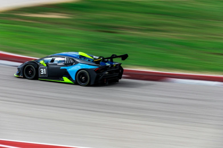 a car drives on a race track with the grass in the background