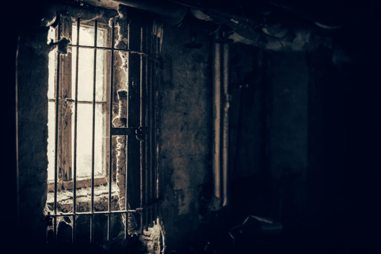 a prison cell in an abandoned building with bars on one window