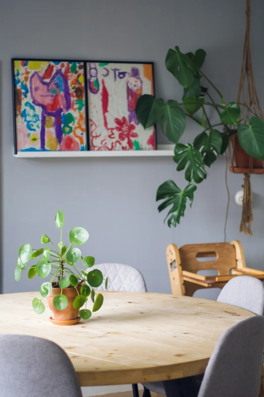 a wooden table and chairs in front of paintings