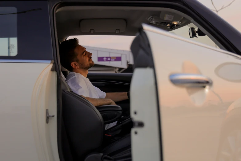 a man sitting inside of a car with his hands in the back seat