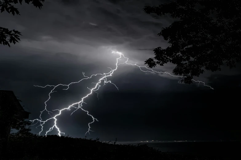 a large bolts of lightning in the sky above some trees