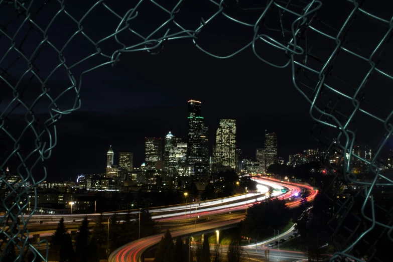 a city skyline at night seen through the fence