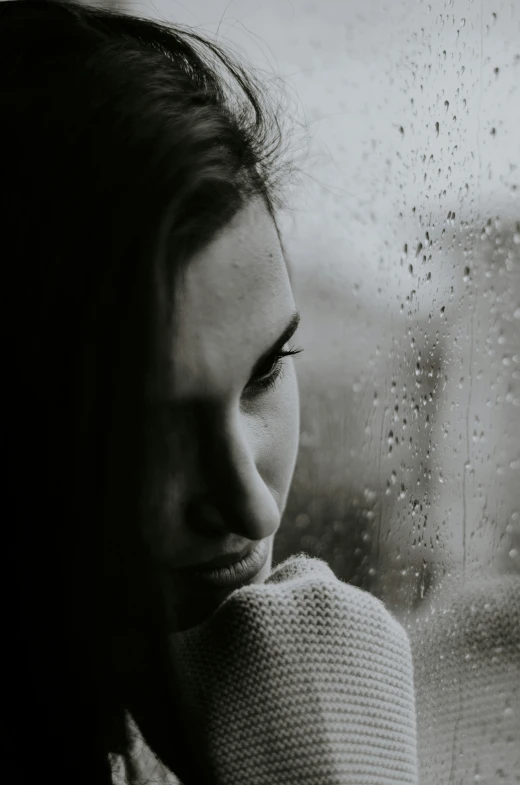 a woman looking out a window on a rainy day