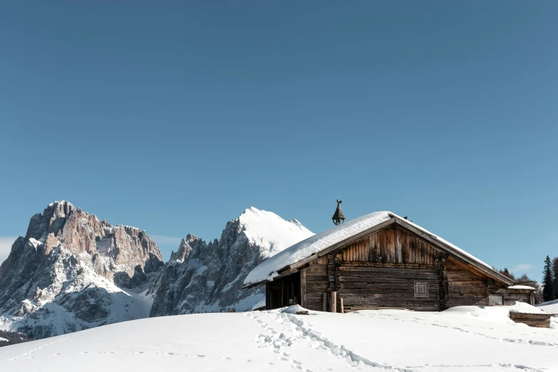 the barn sits at the bottom of a snowy mountain