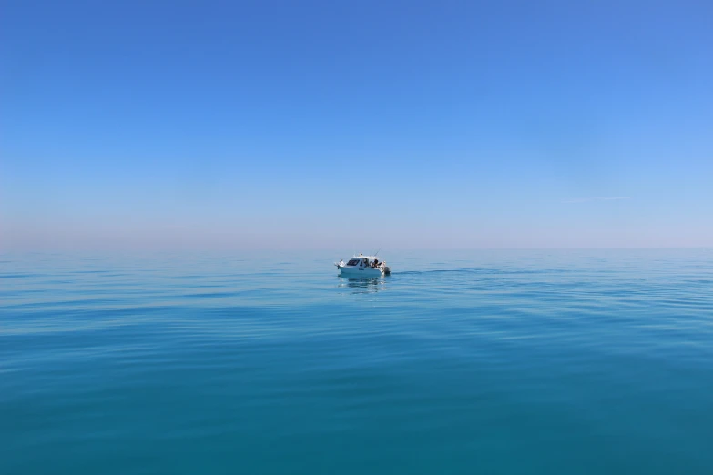 a small boat floating in the ocean with a clear sky