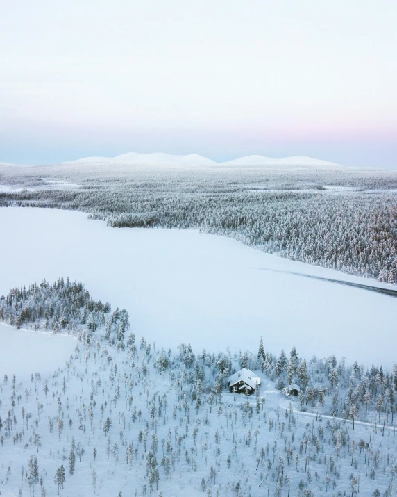 an aerial view of a snowy lake surrounded by evergreen trees