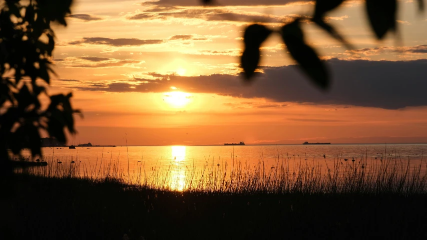 sunset over the water with boats anchored at sea