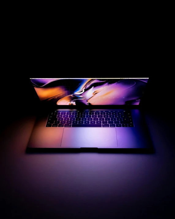 an open laptop computer is lit up by a spotlight