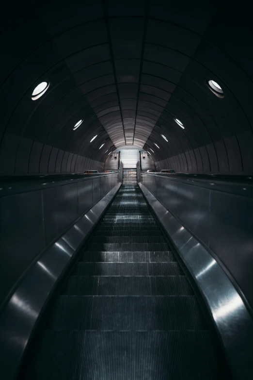 a dark subway with three sets of escalators at one end