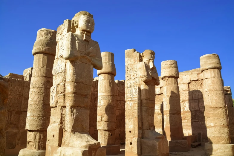 a statue in between two giant columns, in the background is a blue sky