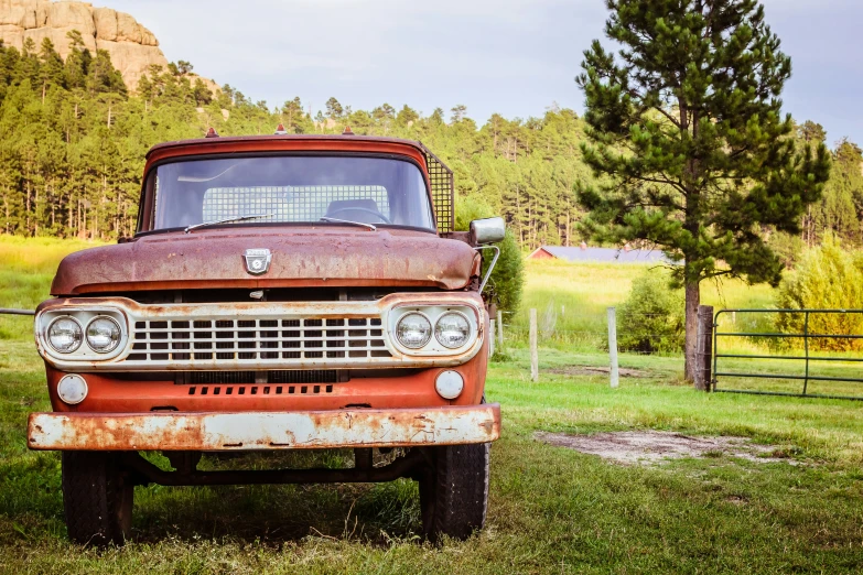 an old truck sitting in the grass with its headlights on