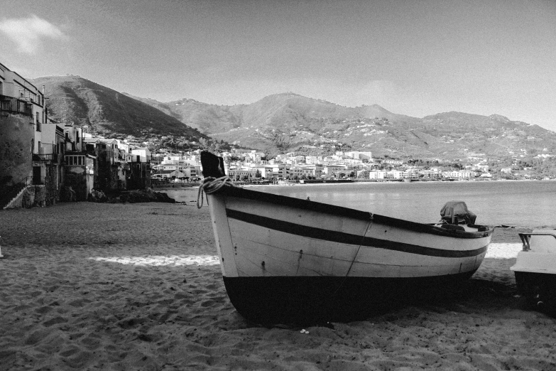 boat sitting in water on sandy beach in front of city