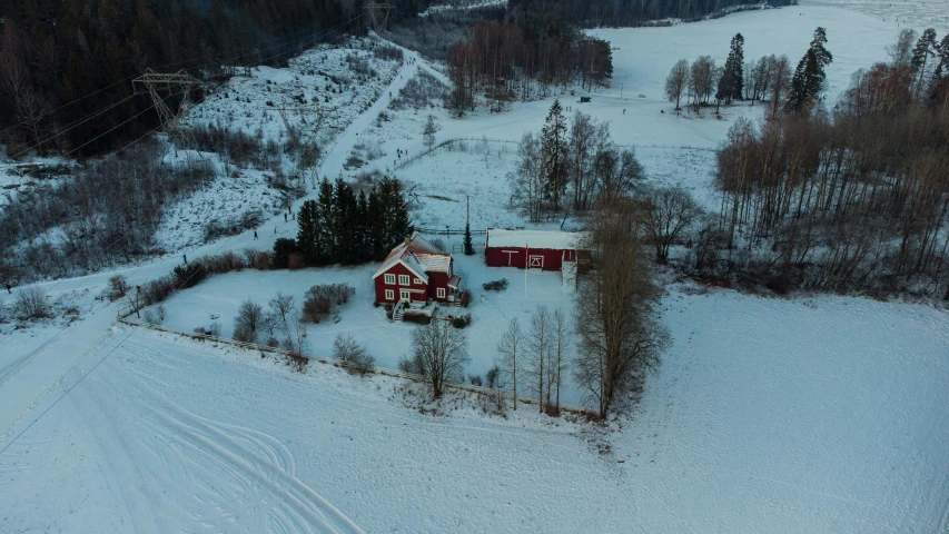 a red cabin is perched next to trees in the snow