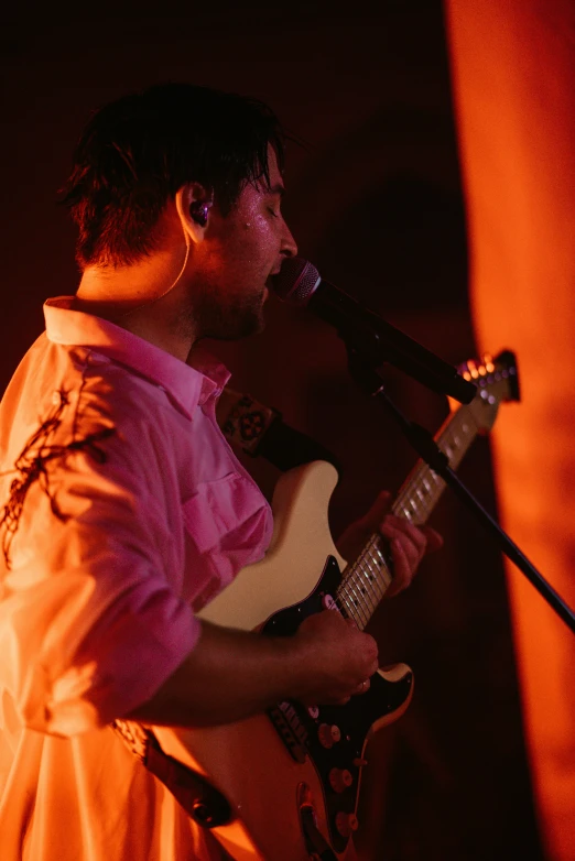 a man playing the guitar in a room with red lighting